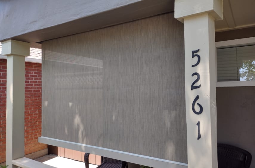 A residence showcasing a front porch adorned with a large shade covering and a drop screen by Goodwin-Cole, enhancing outdoor enjoyment.