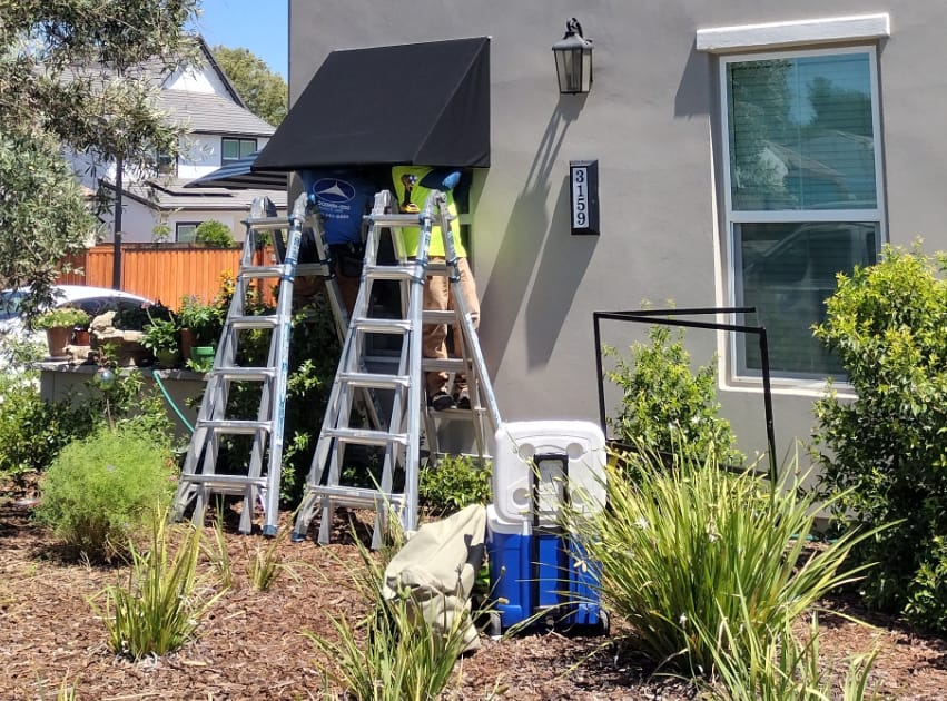 Work is underway for a black fabric residential awning installation.