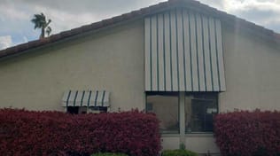 Green and white stripe fabric window awning, residential.